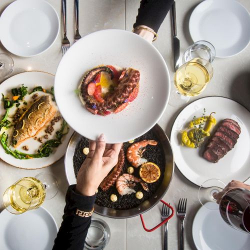 A top-down view of a meal spread with assorted dishes, bowls, and utensils around a central plate.