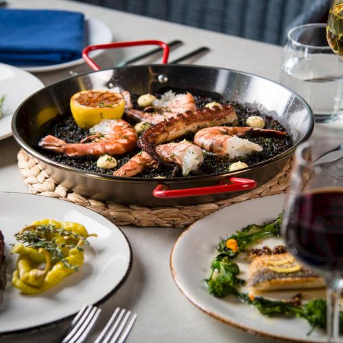 A spread of desserts and tapas: chocolate treats, fruit, and assorted small bites on a white plate, with colorful bowls and drinks nearby.